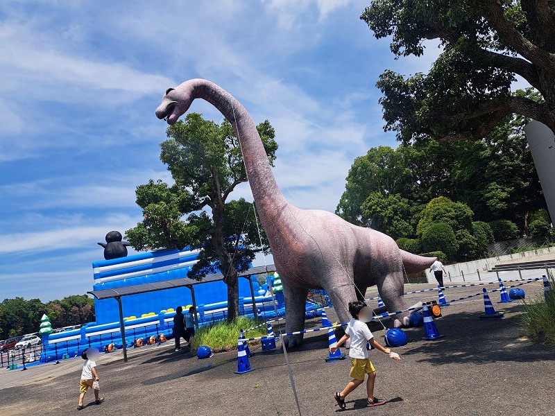 ブラキオサウルスミストバルーンの前で走って遊ぶお子様